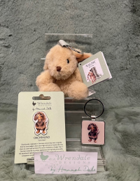 Wrendale Dog Accessories - These accessories will be the paw-fect addition to your keys or outfit! 

They make a great treat for yourself or someone special. 

The wonderful dachshund pin badge will add an extra flourish to your jacket, scarf and bag or pin board. 

Never lose your keys again with these delightful keyrings. A simple yet adorable metal keyring or a stand out gorgeous plush animal. 

*PLEASE SELECT THE PRICE *
*STANDARD- DOG PIN*
*DELUXE- DOG KEYRING(METAL)*
*LUXURY- PLUSH DOG KEYRING*
*ITEM IS ONLY AVAILABLE AS AN ADD ON GIFT OR FOR COLLECTION*
*LIMITED AVAILABILITY*
Pin badge details- Badge 35mm, backing card 105mmx75mm.  Each pin badge comes on information card with a to/from section on the back. Made from alloy with a silver finish. Nickle free and card made from sustainable sourced board. 
Metal keyring details- 4cmx8cm including the ring. Cast in hard wearing zinc alloy metal with a resin domed finish on the front.
Plush keyring- Measures 100mm x 70mm x 70mm. Finished with a branded woven label and a silver keyring loop perfect for attaching to keys and bags. Made with quality soft and tactile materials with polyester fiber stuffing. Recommended for children 3 years +.